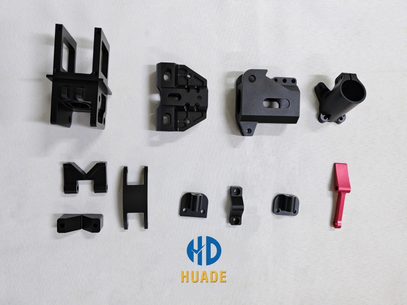 Assortment of CNC machined black aluminum NATO mounts and clamps for drones, including brackets and red quick-release lever.